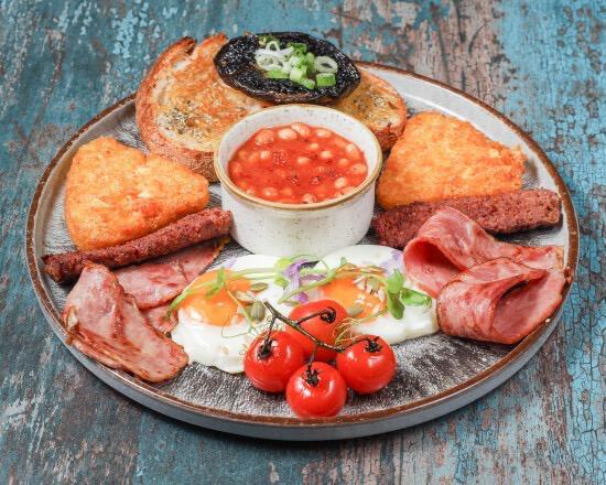 Full English breakfast with eggs, bacon, sausage, hash browns, beans and mushrooms