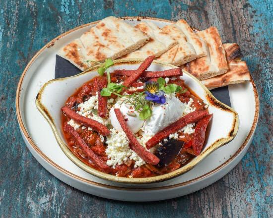 Shakshuka with sucuk, poached eggs in tomato sauce with feta and Turkish bread