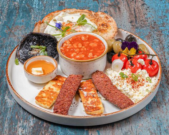 Turkish breakfast plate with sucuk, halloumi, feta, olives, eggs and beans